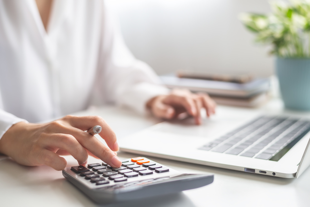 Femme avec calculette devant ordinateur portable